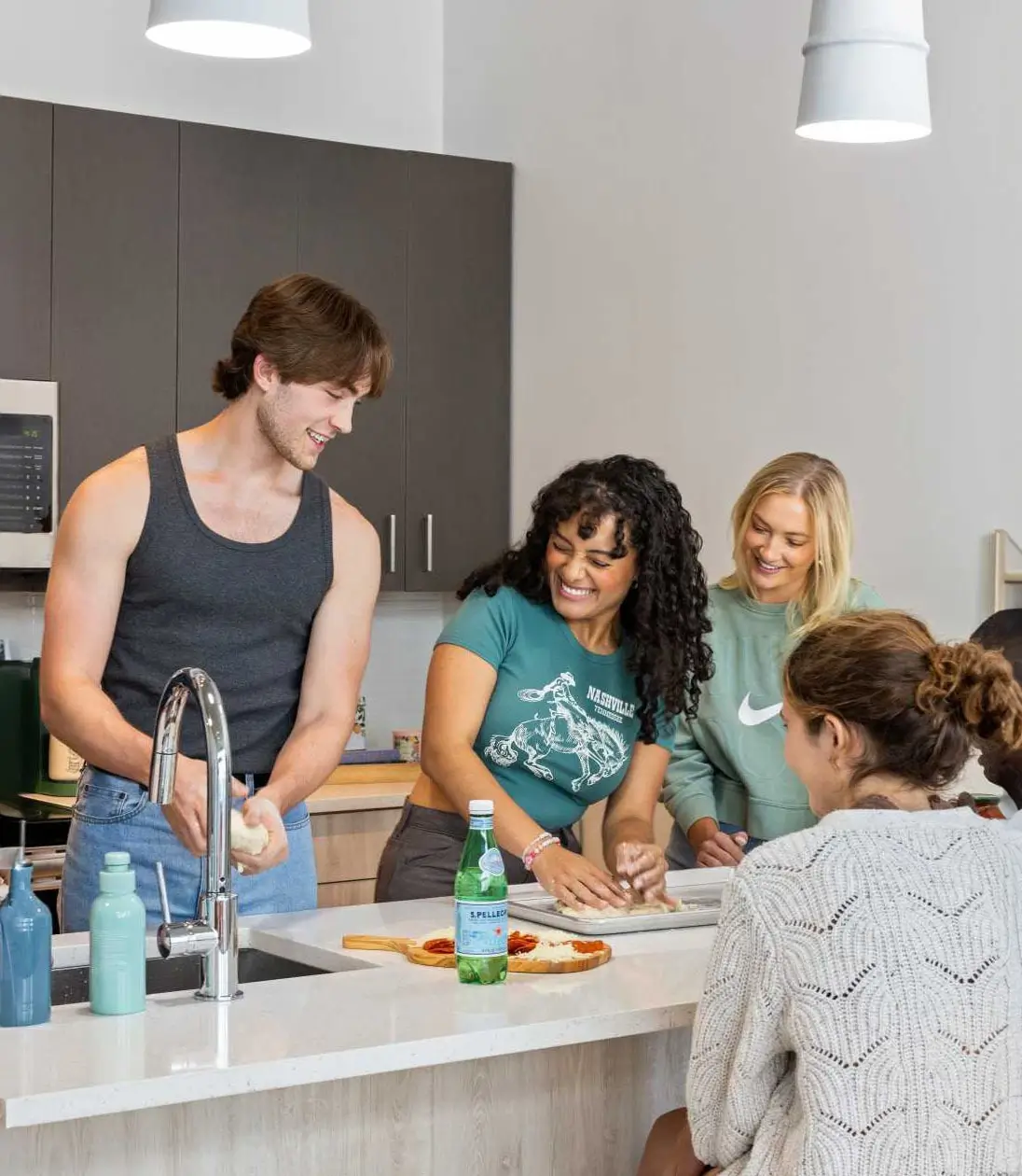 young adults cooking pizza in a kitchen