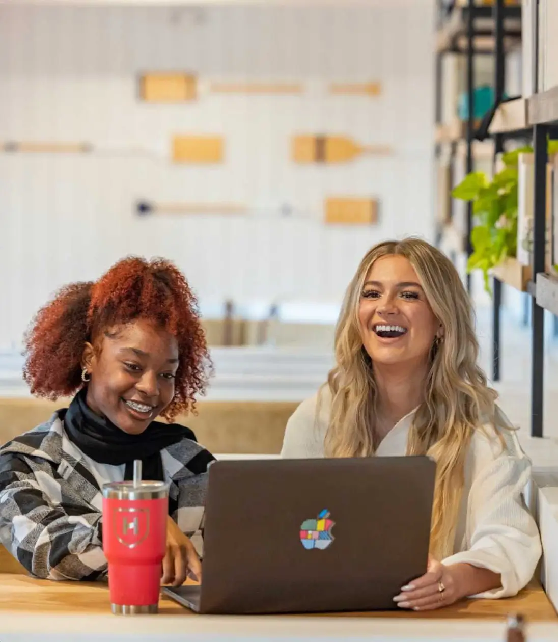two women work on a computer together